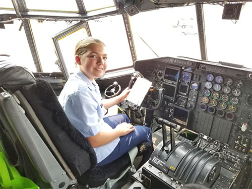 A student seated in the cockpit of a large aircraft